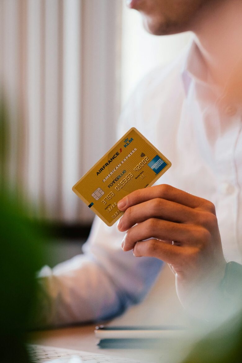 Person holding a credit card, representing everyday grocery and gas purchases