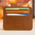 A brown leather wallet holding several credit cards, one of them unused