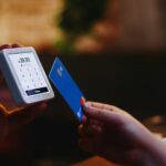 Person holding a credit card and checking a mobile payment app on a phone