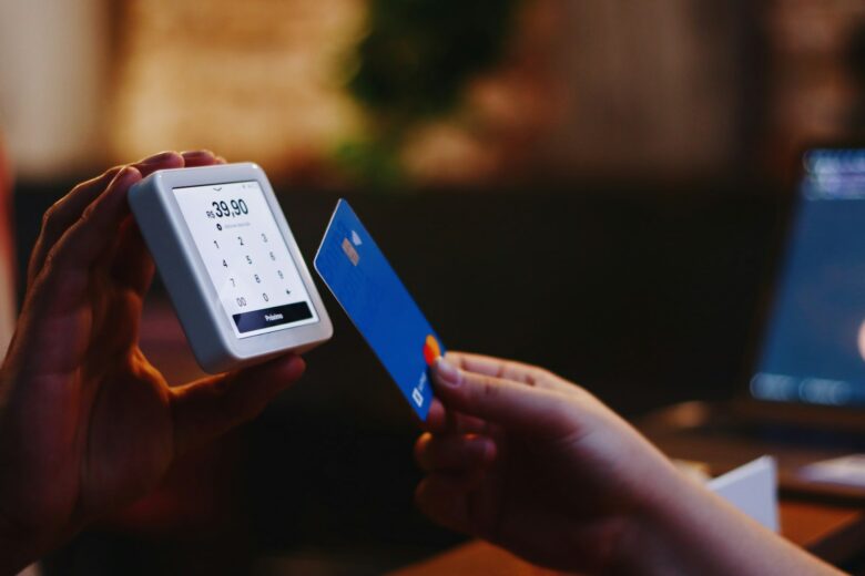 Person holding a credit card and checking a mobile payment app on a phone