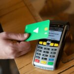 Person holding a credit card next to a calculator while reviewing bills