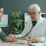Doctor checking a patient's blood pressure with a stethoscope, representing a medical visit that can lead to a bill