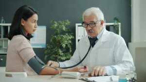 Doctor checking a patient's blood pressure with a stethoscope, representing a medical visit that can lead to a bill