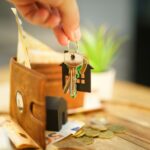 Hand holding a set of house keys with a wallet, representing paying rent each month