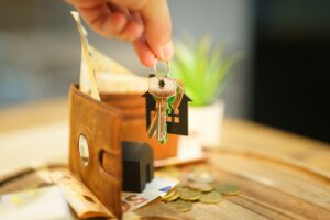 Hand holding a set of house keys with a wallet, representing paying rent each month